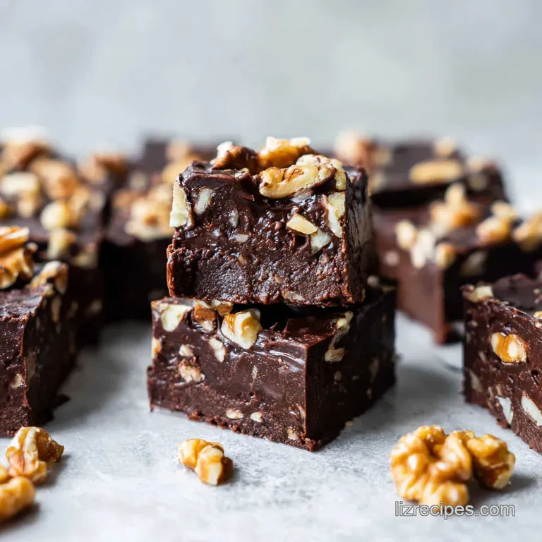 Dark chocolate cubes stacked on a slate board, accented by a dusting of cocoa powder and fresh mint leaves.