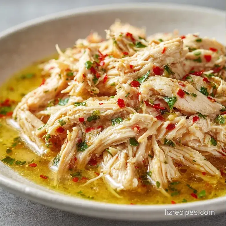 Neatly piled tender chicken shreds garnished with chopped parsley and a drizzle of savory golden pan sauce.